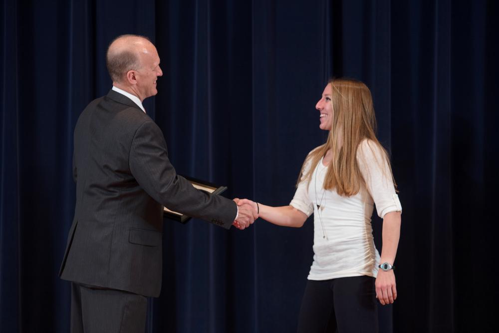 Doctor Potteiger shaking hands with an award recipient in a long sleeved white shirt